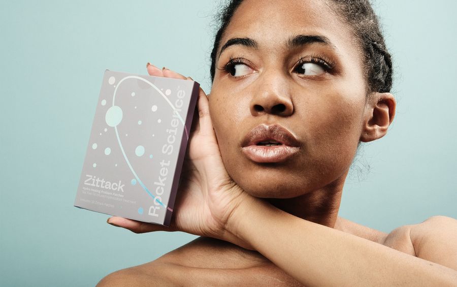 Woman holding a Rocket Science Zittack packaging near her face